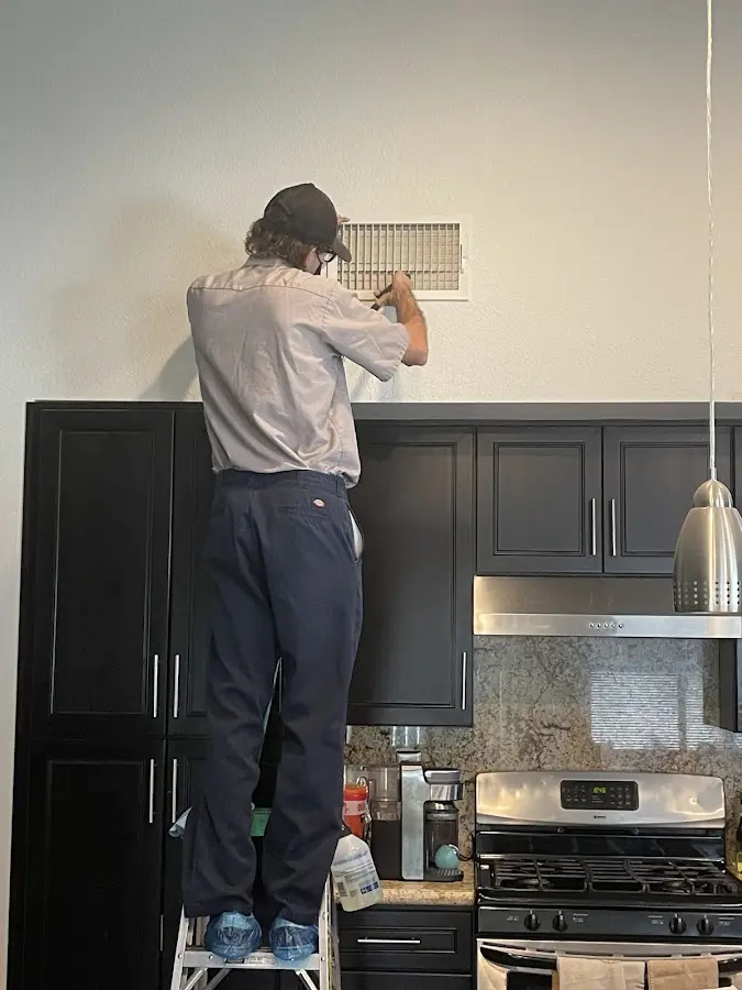 Technician inspecting an air vent during HVAC service in Damascus
